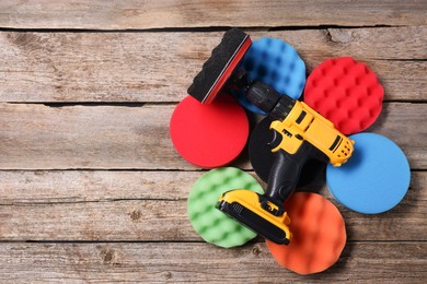 Photo of Electric screwdriver with different polish pads on wooden background, top view. Space for text