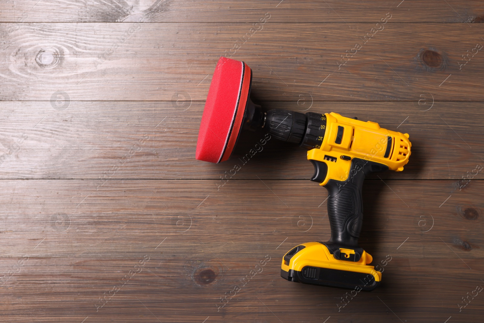 Photo of Electric screwdriver with polish pad on wooden background, top view. Space for text