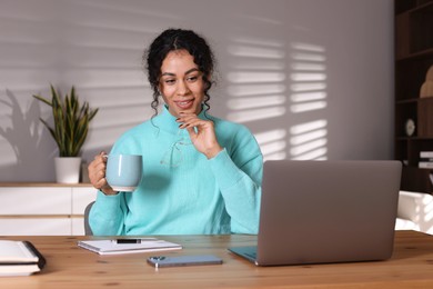 Photo of Beautiful woman working on laptop at desk in home office