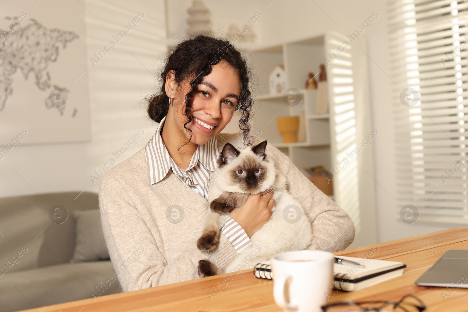 Photo of Beautiful woman with her cute cat working at desk in home office