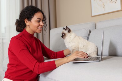 Photo of Beautiful woman with her cute cat working on laptop at home