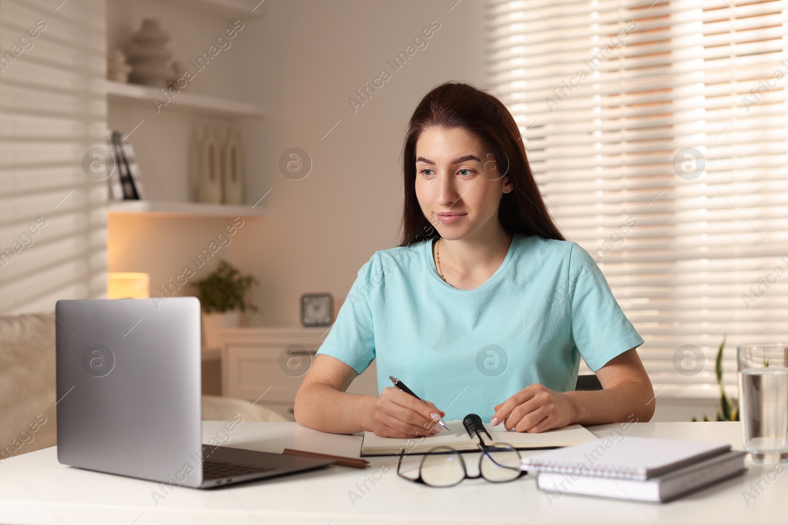 Photo of Young woman working on laptop at desk in home office