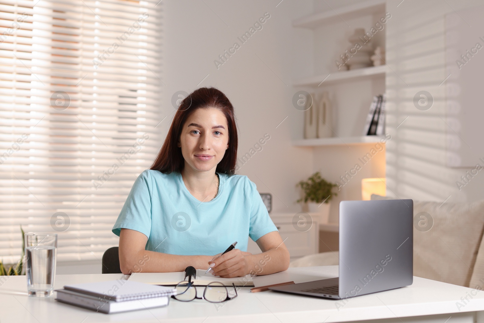 Photo of Young woman working on laptop at desk in home office