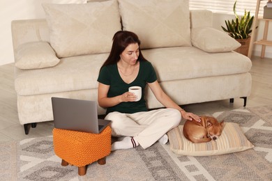 Young woman working on laptop while her cute dog sleeping beside at home