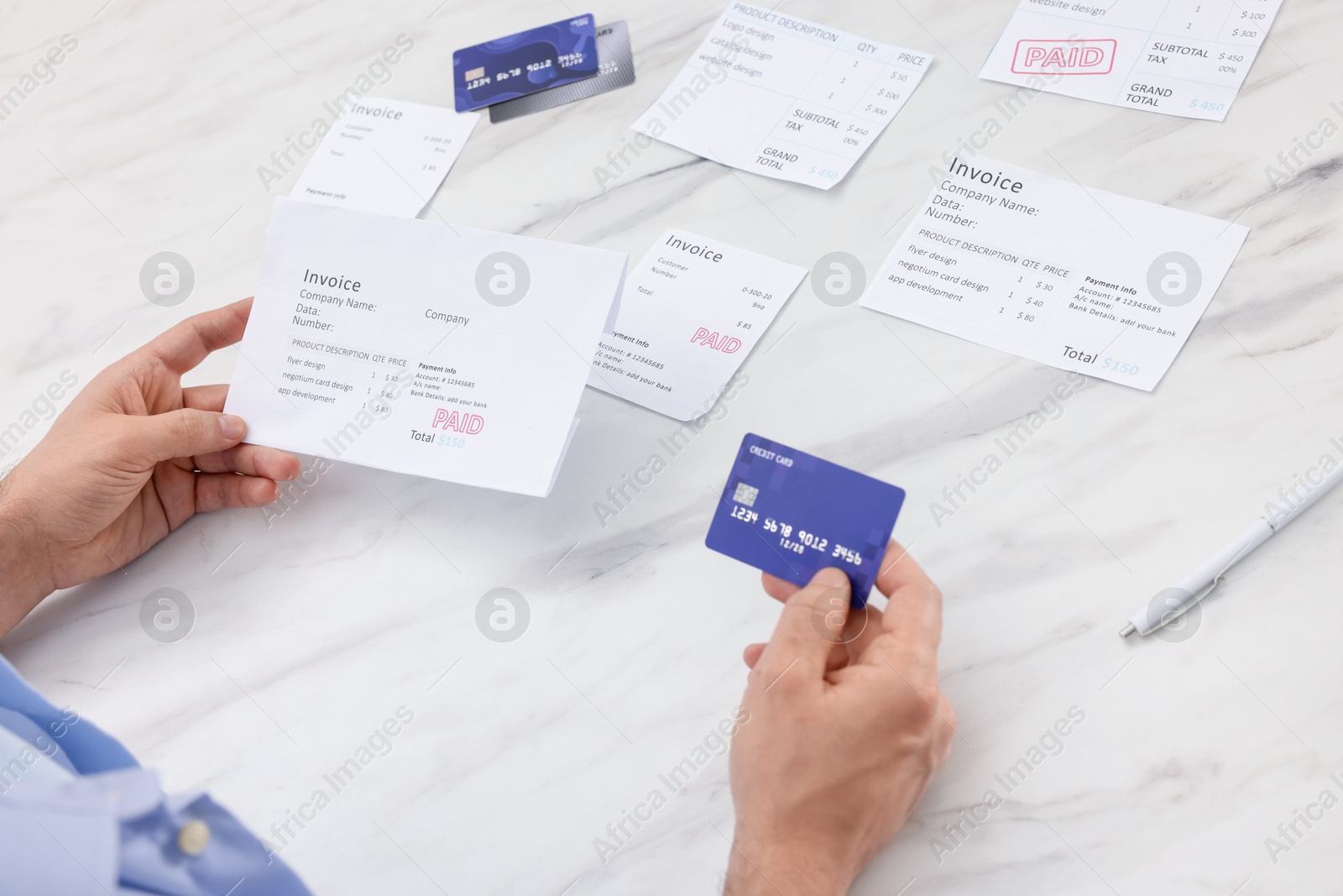 Photo of Paying bills. Man with different invoices and credit cards at white marble table, closeup