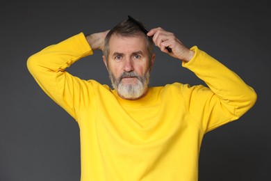 Photo of Handsome man combing his hair on dark grey background