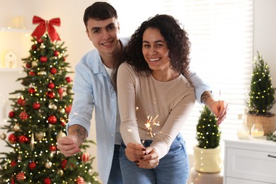 Photo of Happy couple with burning sparklers spending time together at home. Christmas celebration