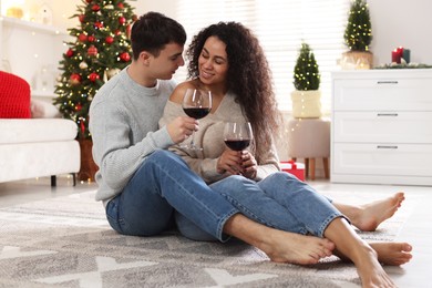 Happy couple with glasses of wine spending time together at home. Christmas celebration