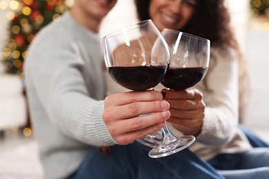 Photo of Happy couple with glasses of wine at home, selective focus. Christmas celebration