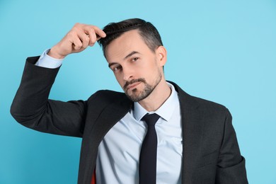 Photo of Handsome man stylish his hair with comb on light blue background