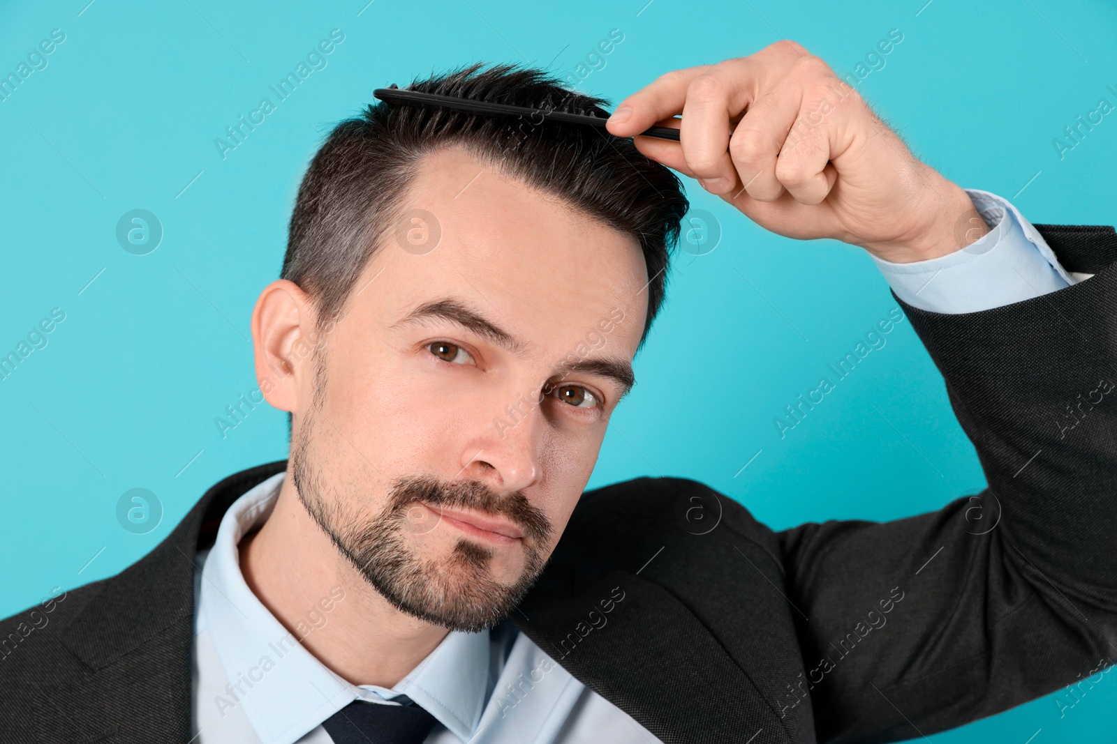 Photo of Handsome man stylish his hair with comb on light blue background