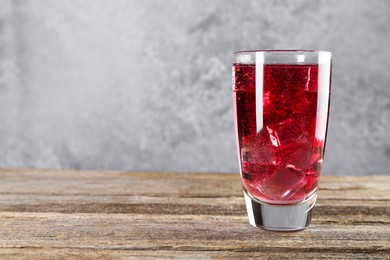 Photo of Sweet soda water with ice cubes in glass on wooden table, space for text