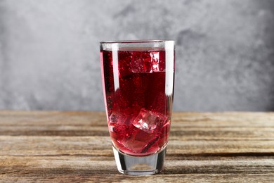 Photo of Sweet soda water with ice cubes in glass on wooden table