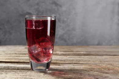 Photo of Sweet soda water with ice cubes in glass on wooden table, space for text