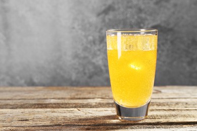 Photo of Sweet soda water with ice cubes in glass on wooden table, space for text