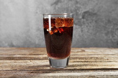 Photo of Sweet soda water with ice cubes in glass on wooden table