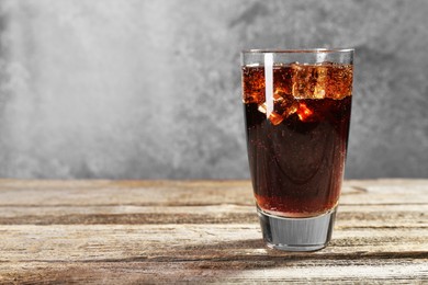 Photo of Sweet soda water with ice cubes in glass on wooden table, space for text