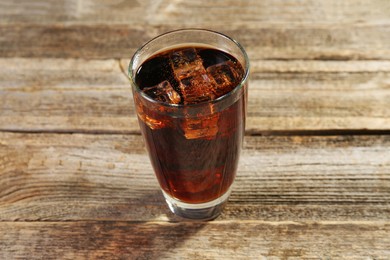 Photo of Sweet soda water with ice cubes in glass on wooden table, closeup