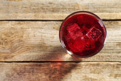 Photo of Sweet soda water with ice cubes in glass on wooden table, top view. Space for text