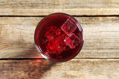 Photo of Sweet soda water with ice cubes in glass on wooden table, top view