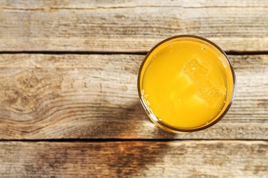 Photo of Sweet soda water with ice cubes in glass on wooden table, top view. Space for text