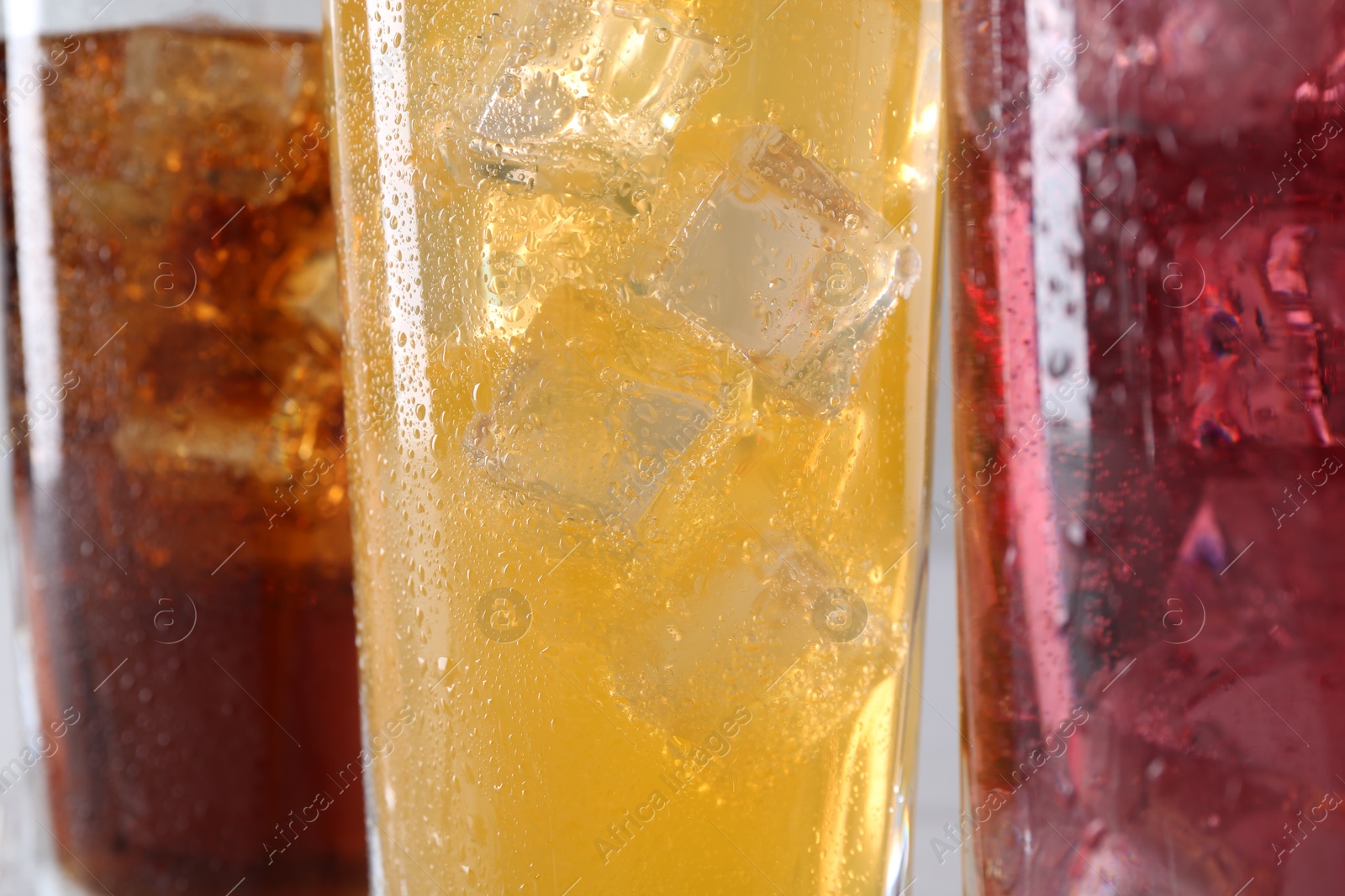 Photo of Soda water of different flavors with ice cubes in glasses, closeup