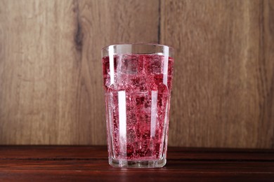 Photo of Sweet soda water with ice cubes in glass on wooden table