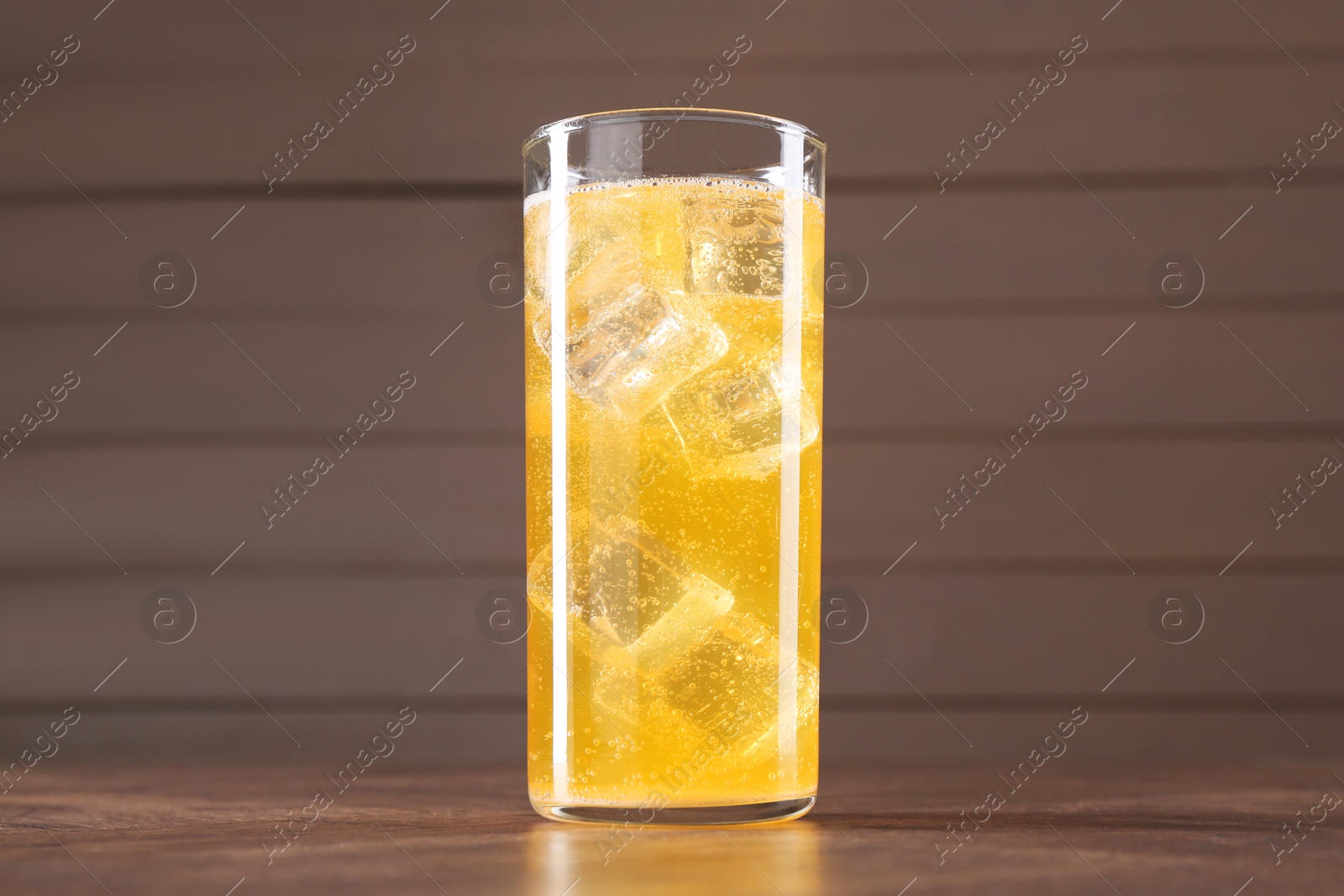 Photo of Sweet soda water with ice cubes in glass on wooden table