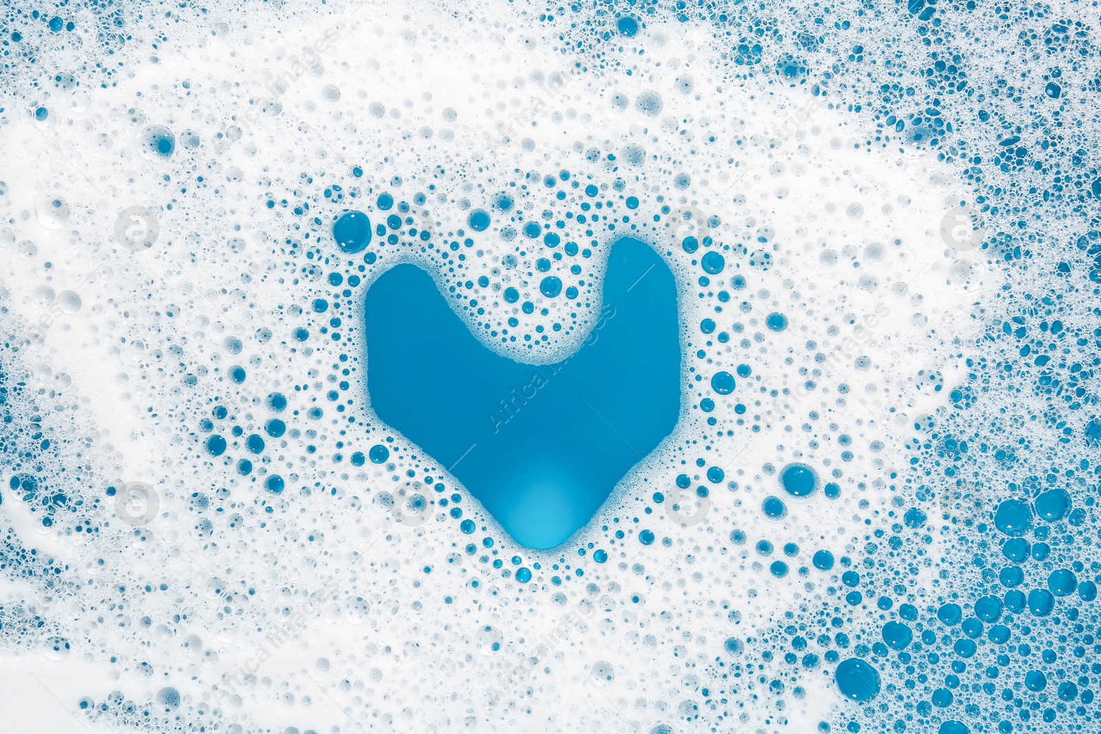 Photo of Heart shape made of detergent foam on light blue background, top view