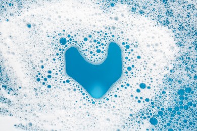 Photo of Heart shape made of detergent foam on light blue background, top view