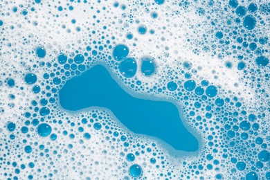 Photo of Detergent foam with bubbles on light blue background, top view