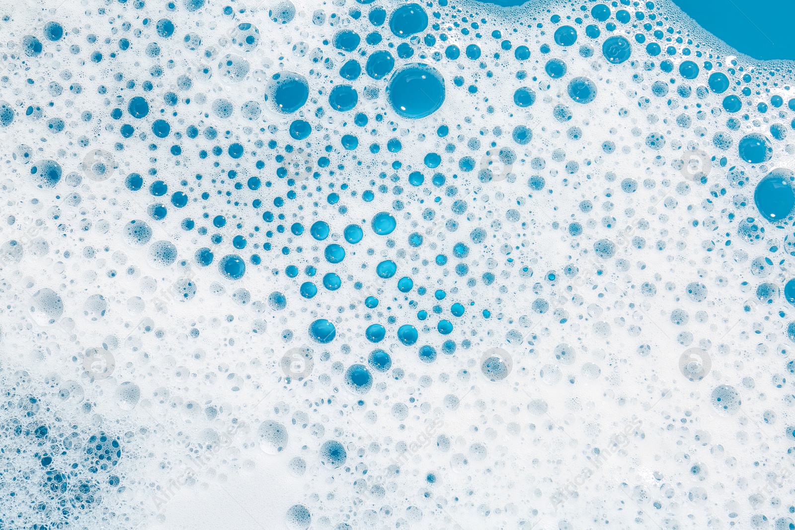 Photo of Detergent foam with bubbles on light blue background, top view