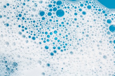 Photo of Detergent foam with bubbles on light blue background, top view