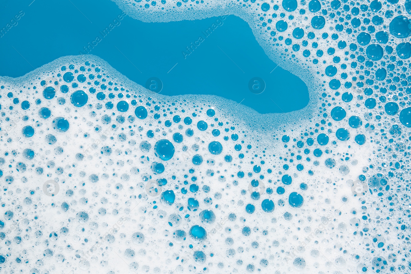 Photo of Detergent foam with bubbles on light blue background, top view