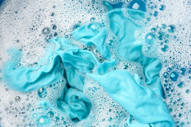 Photo of Turquoise clothes soaked in water before washing, top view