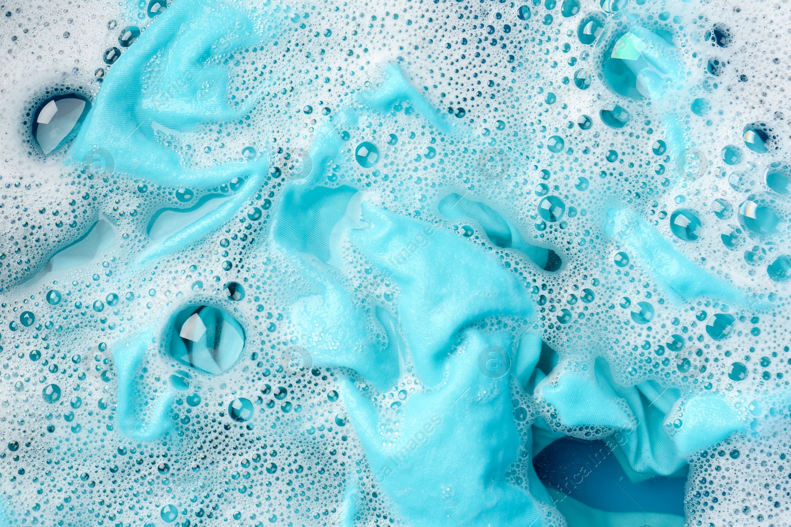 Photo of Turquoise clothes soaked in water before washing, top view