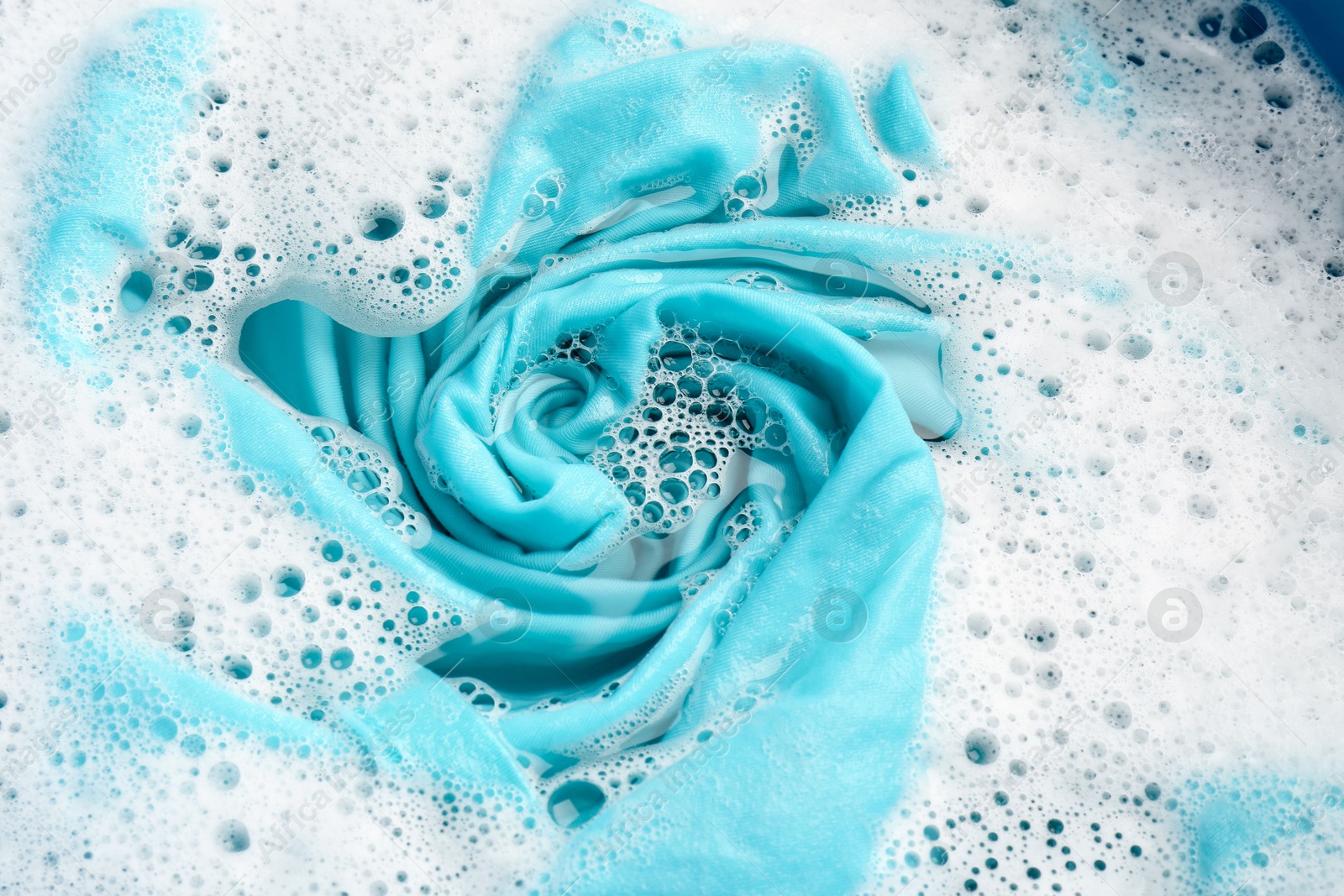 Photo of Turquoise clothes soaked in water before washing, closeup