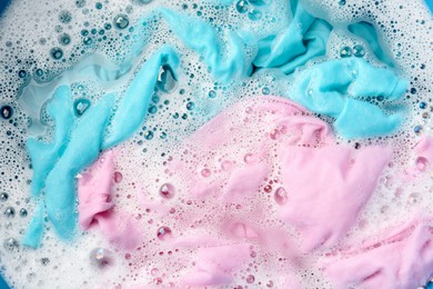 Photo of Colorful clothes soaked in water before washing, top view