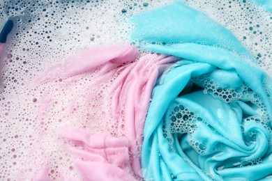 Photo of Colorful clothes soaked in water before washing, top view