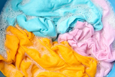 Photo of Colorful clothes soaked in water before washing, top view