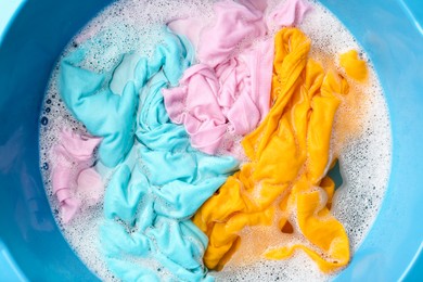 Photo of Colorful clothes soaked in water before washing, top view