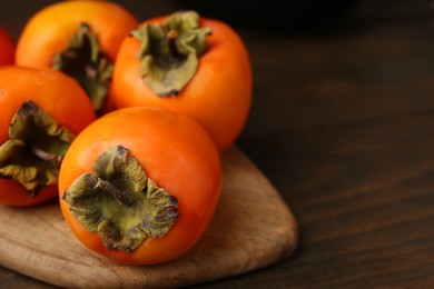 Delicious fresh juicy persimmons on wooden table, closeup. Space for text