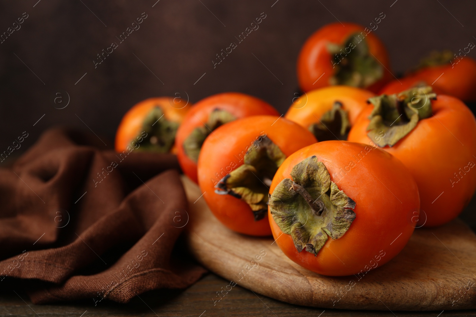 Photo of Delicious fresh juicy persimmons on wooden table, closeup