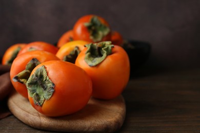 Photo of Delicious fresh juicy persimmons on wooden table, closeup. Space for text