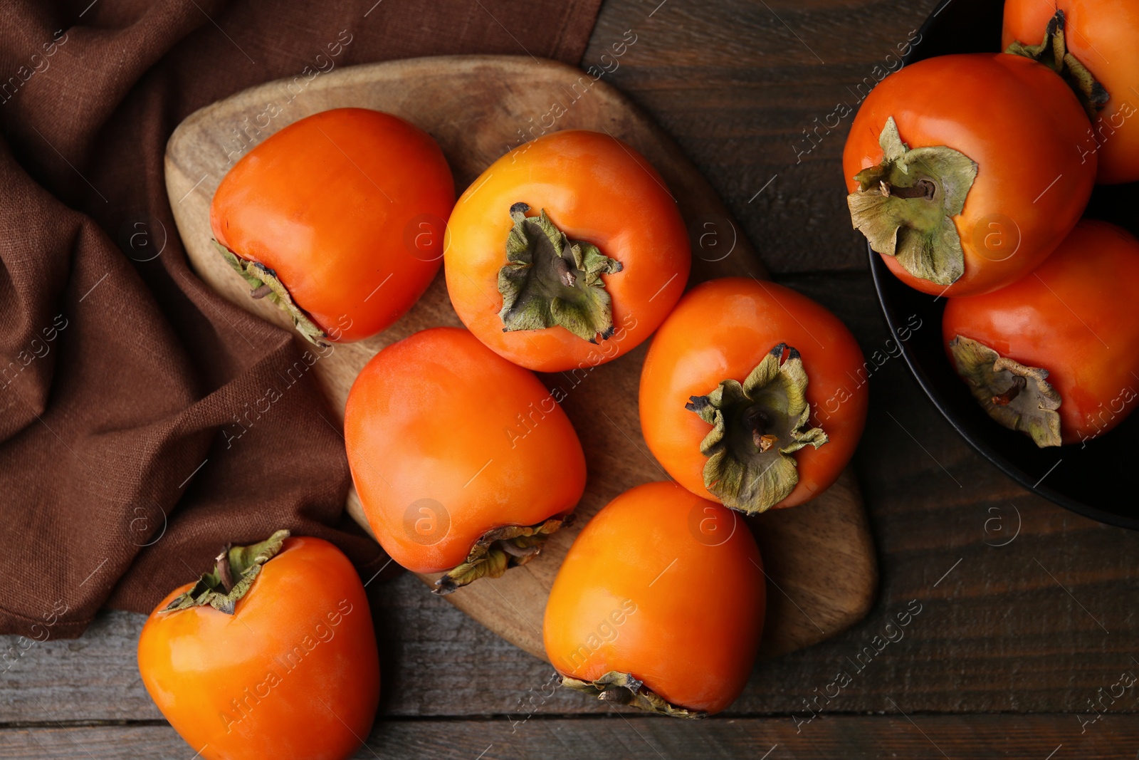 Photo of Delicious ripe juicy persimmons on wooden table, flat lay