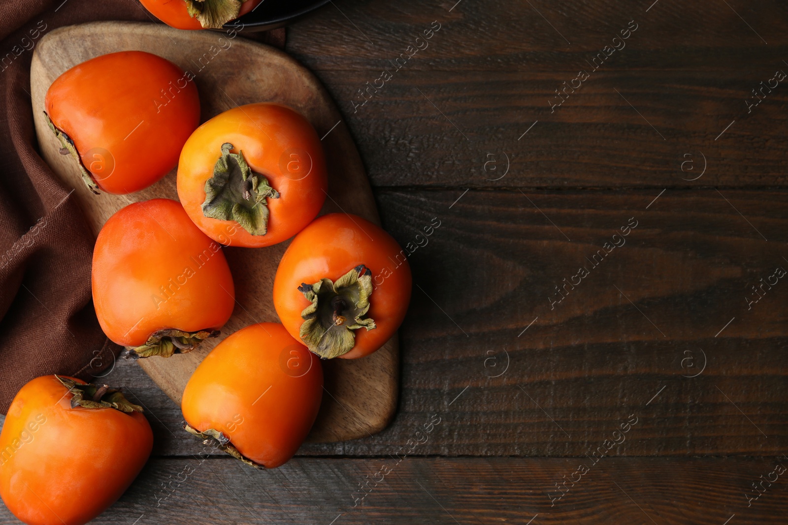 Photo of Delicious ripe juicy persimmons on wooden table, flat lay. Space for text