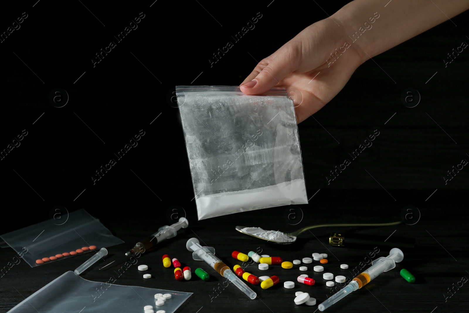 Photo of Drug addiction. Woman holding plastic bag with powder against dark background, closeup