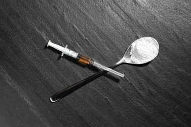 Photo of Drug addiction. Spoon with powder and syringe on dark textured table, flat lay