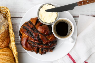 Photo of Delicious poppy seed pastry, butter and coffee on white wooden table, top view