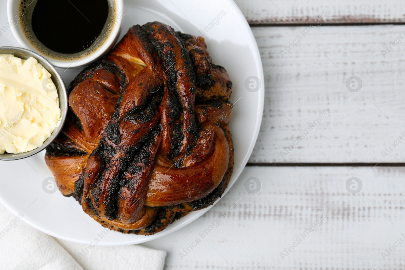 Photo of Delicious poppy seed pastry, butter and coffee on white wooden table, top view